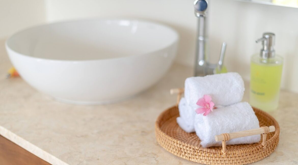 Coastal Bathroom Ideas: Small Bathroom Before and After 1 Rolled white towels on a round rattan tray next to a white bowl sink, a spa-like coastal bathroom detail