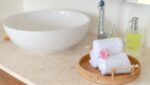 Coastal Bathroom Ideas: Small Bathroom Before and After 9 Rolled white towels on a round rattan tray next to a white bowl sink, a spa-like coastal bathroom detail