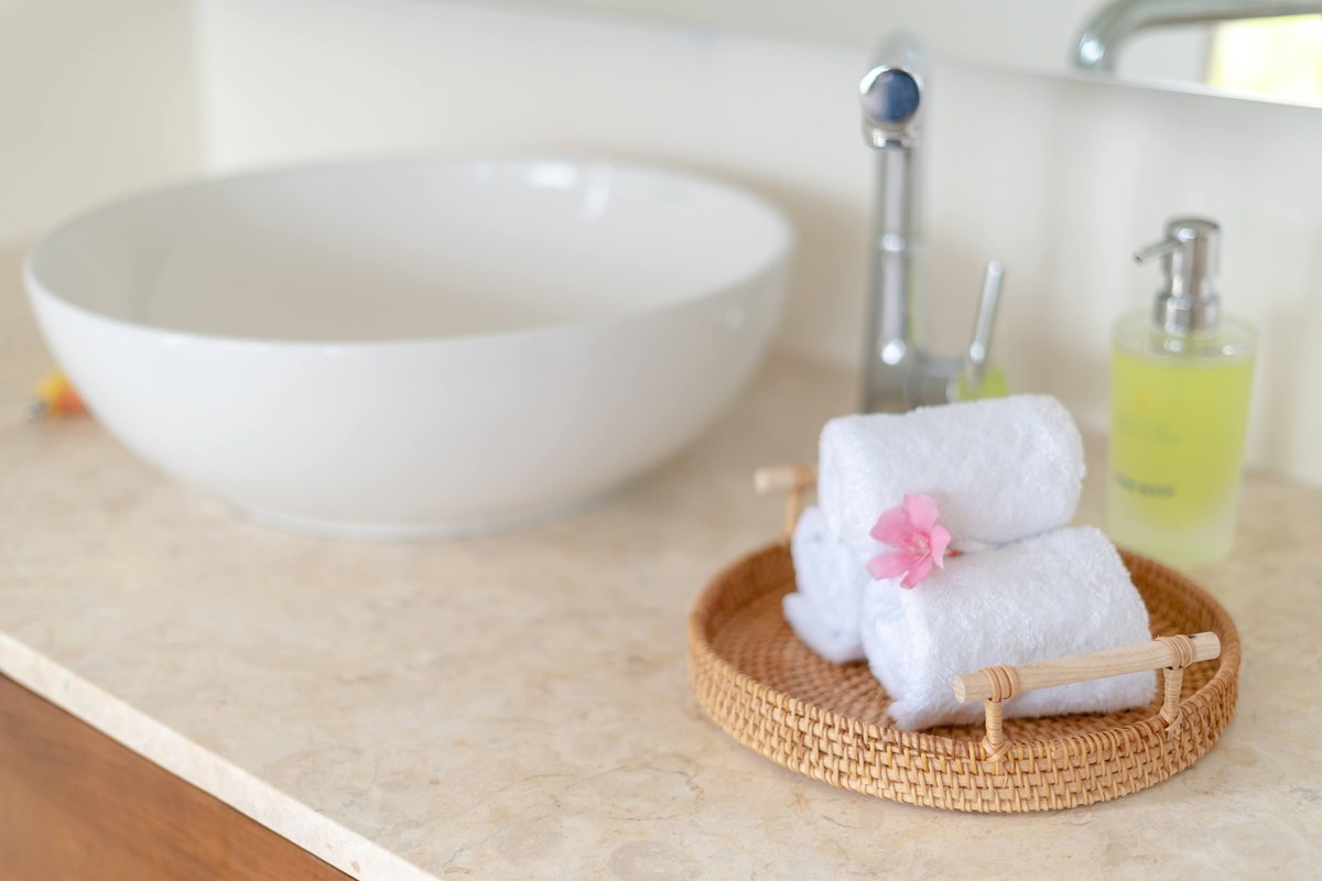 Coastal Bathroom Ideas: Small Bathroom Before and After 3 Rolled white towels on a round rattan tray next to a white bowl sink, a spa-like coastal bathroom detail